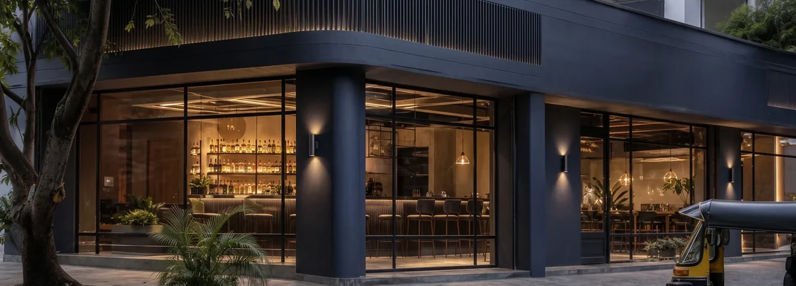 Corner restaurant frontage with a navy fascia band, full-height glazing and a lit bar counter visible inside