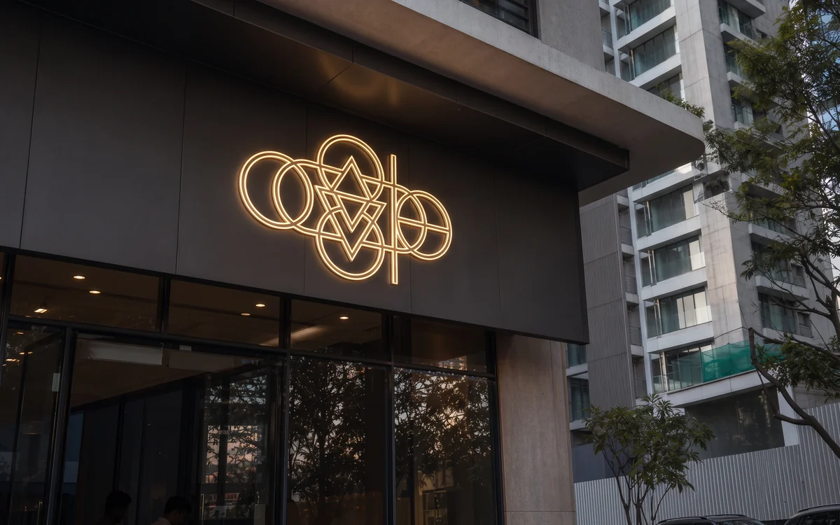 Line-art logo glowing on the dark facade of a building at dusk