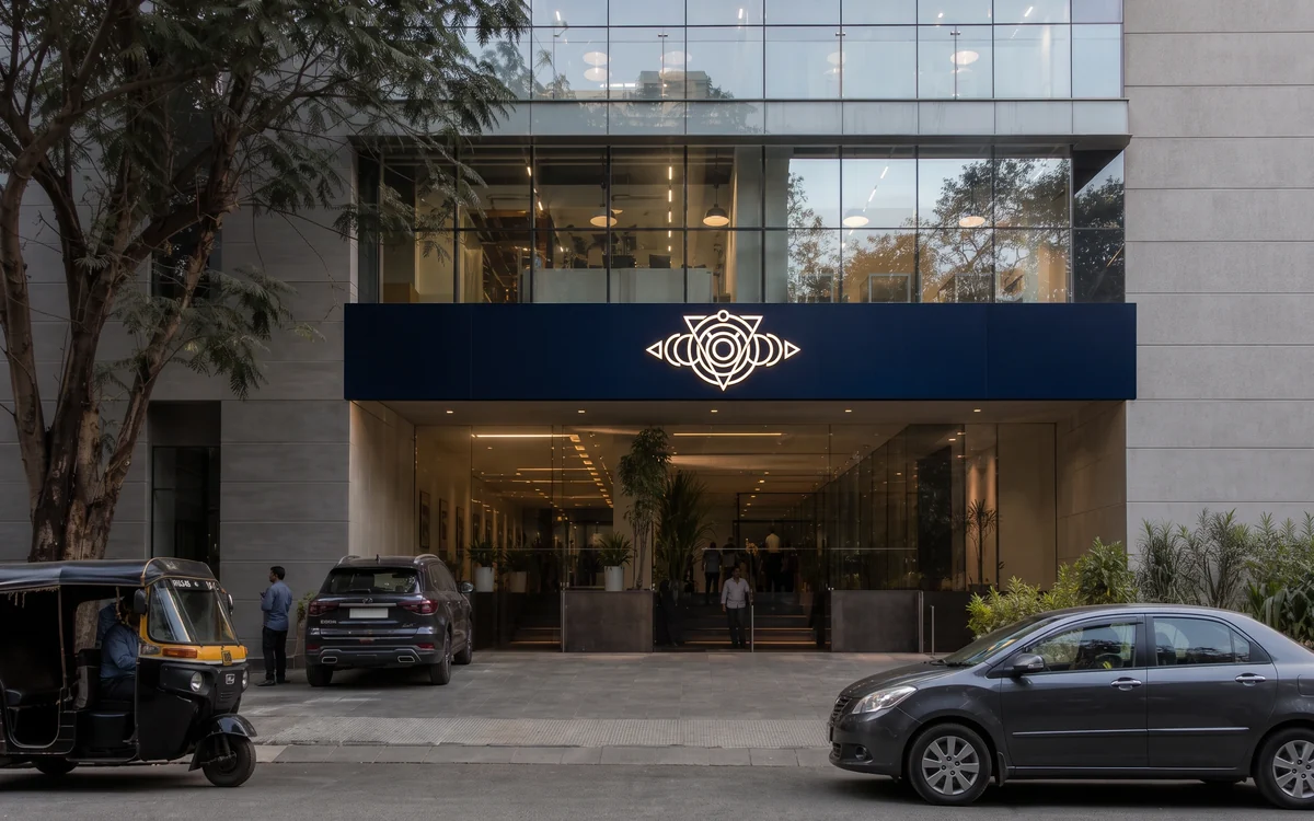 Office building entrance with a navy name board and logo above the glass front
